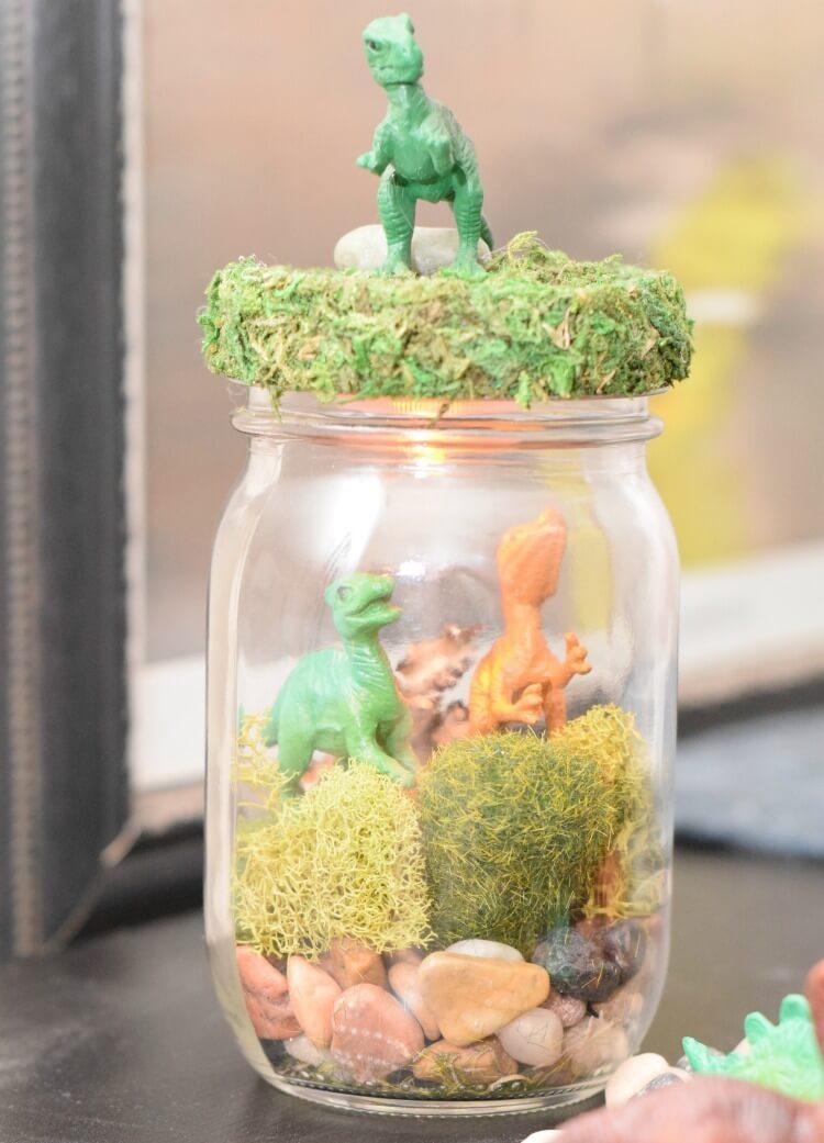 A jar with plants and toy dinosaurs inside